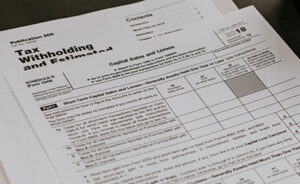 A close-up of IRS tax forms, including Schedule D and Publication 505, showing sections for capital gains and losses and estimated tax calculations.